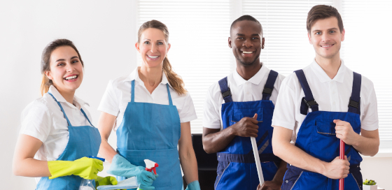 Gruppenbild mit 4 Reinigungskräfte, zwei Frauen und zwei Männer, bei der Arbeit.
